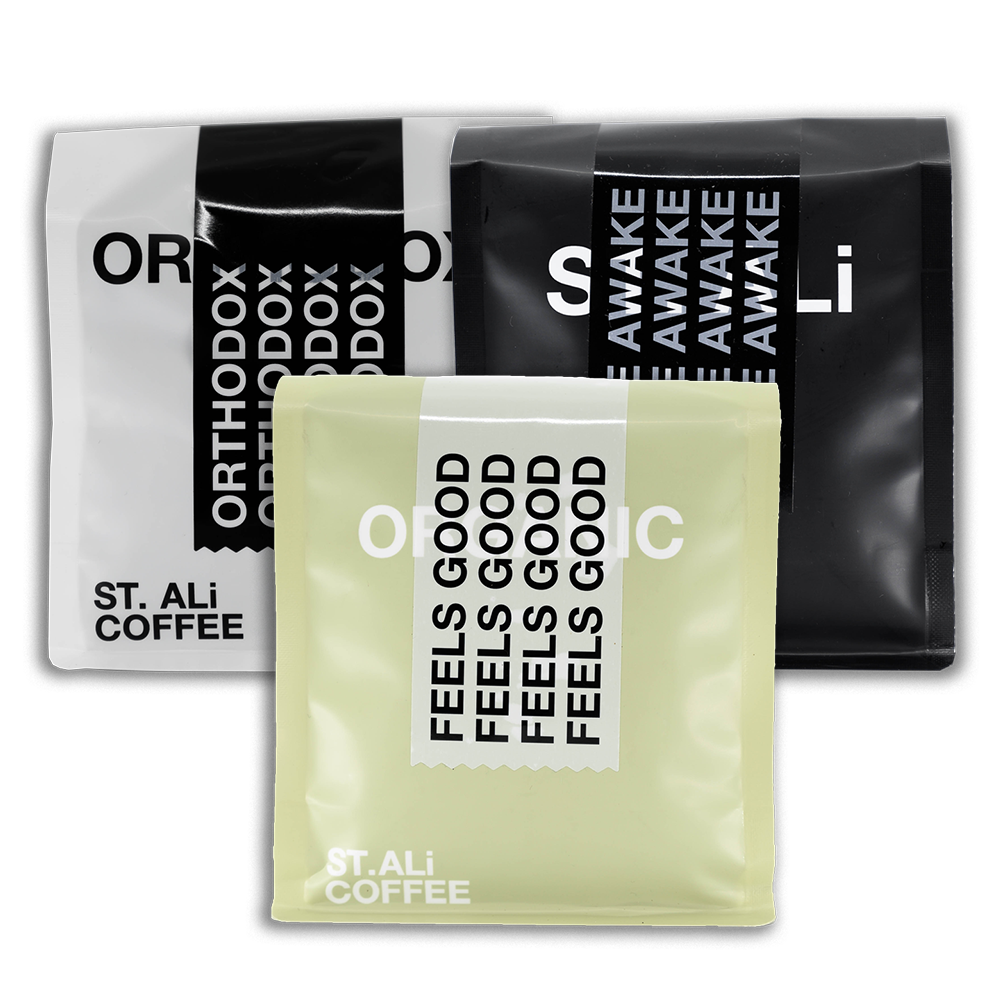 3 bags of 250 gram  of coffee. 1 bag in front and 2 behind it on either side. A white, Black & Pale green bag with white & black text.